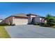 Exterior of the house with a gray driveway, two-car garage, and neatly landscaped yard at 2112 Purple Orchid Pl, Ruskin, FL 33570