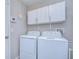 Functional laundry room with white washer and dryer, white storage cabinets, and a wall-mounted ironing board at 2112 Purple Orchid Pl, Ruskin, FL 33570