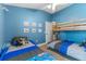 Spacious bedroom with blue walls, featuring a bunk bed and a twin bed, offering a comfortable and playful space at 38205 Countryside Pl, Dade City, FL 33525