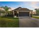 Inviting home exterior featuring a well-manicured lawn, palm tree, and a two-car garage at 38205 Countryside Pl, Dade City, FL 33525