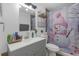 Well-lit bathroom featuring a gray vanity, modern fixtures, and a quirky shower curtain at 4077 Ramona Dr, Spring Hill, FL 34606