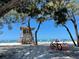 Picturesque beach view with a lifeguard station framed by trees and bike rack at 610 Casabella Dr, Bradenton, FL 34209