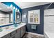 The bathroom has blue walls, two vanity mirrors, a shower, and a gray vanity with white countertops at 6326 Brevada Ln, Apollo Beach, FL 33572