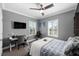 This bedroom features gray walls, a bed, a ceiling fan, a white desk, and two windows with white shutters at 6326 Brevada Ln, Apollo Beach, FL 33572