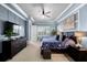 The home's main bedroom has blue walls with white trim, a tray ceiling, a ceiling fan, and a dark-wood dresser with a tv on top at 6326 Brevada Ln, Apollo Beach, FL 33572