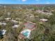 An aerial view of a neighborhood showcasing community tennis courts and pool amidst lush greenery and mature trees at 712 1St Ct, Palm Harbor, FL 34684