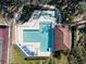 Aerial view of a beautiful pool area with an inground spa, surrounded by lush greenery and a tennis court at 712 1St Ct, Palm Harbor, FL 34684