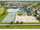 An aerial view shows a tennis court, playground, basketball court, and a pool with lounge chairs at 7945 Carriage Pointe Dr, Gibsonton, FL 33534