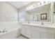 Bathroom featuring a double-sink vanity, large mirror, soaking tub and a separate shower at 7945 Carriage Pointe Dr, Gibsonton, FL 33534