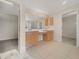 Bathroom featuring dual vanities with warm-toned cabinetry, tile flooring, and doorways to the closets at 9003 Willowbrook Cir, Bradenton, FL 34212