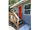 Close up of a home's front door and porch area with wood stairs and gray exterior siding at 910 Seminole St, Clearwater, FL 33755