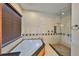 Luxurious bathroom with a glass shower, soaking tub, and travertine tile at 912 Symphony Beach Ln, Apollo Beach, FL 33572