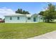 Inviting single-story home with light-blue paint, white metal roof, and lush green lawn at 9321 Regatta Cir, Spring Hill, FL 34606