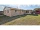 Back exterior of house with small shed and stucco exterior and large lawn at 5117 Cape Cod Dr, Holiday, FL 34690