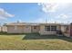 Back exterior view features a well-maintained lawn and stucco exterior with a view of the shed at 5117 Cape Cod Dr, Holiday, FL 34690