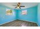 Bedroom with wood-look floors, ceiling fan, and natural light from two windows at 5117 Cape Cod Dr, Holiday, FL 34690