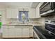 An updated kitchen featuring stainless steel appliances, white cabinets, and granite countertops at 5117 Cape Cod Dr, Holiday, FL 34690