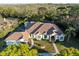 Expansive aerial view of the property highlighting the house's layout, tile roof, and surrounding greenery at 1011 Riverside Ridge Rd, Tarpon Springs, FL 34688
