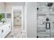 Modern bathroom featuring a glass-enclosed shower with wood-look tile and dual vanities with black hardware at 12339 Hearts Ease St, Venice, FL 34293