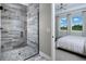 Sleek bathroom glass shower enclosure with a view into a bedroom with large windows and neutral decor at 12339 Hearts Ease St, Venice, FL 34293