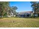 Large, grassy backyard with mature trees and landscaping, leading up to a screened-in pool area at 13255 Don Loop, Spring Hill, FL 34609