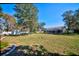 Expansive lawn with mature trees, leading to a screened-in pool area, and fenced yard, ideal for recreation at 13255 Don Loop, Spring Hill, FL 34609