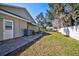 Exterior view of home with a lush, green lawn, patio, and mature shade trees, set against a clear blue sky at 13255 Don Loop, Spring Hill, FL 34609