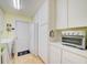 Functional laundry area featuring appliances, storage cabinets, and a white door to the exterior at 13255 Don Loop, Spring Hill, FL 34609