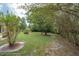 Expansive backyard featuring mature trees, a well-maintained lawn, and a quaint bench for relaxation at 5443 Ott Ct, Spring Hill, FL 34608