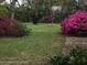 Spacious backyard showcases mature landscaping, including vibrant pink azaleas and whimsical gnome statues at 5443 Ott Ct, Spring Hill, FL 34608