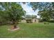 Expansive backyard features mature trees, lush lawn, and an inviting seating area for relaxation and enjoyment at 5443 Ott Ct, Spring Hill, FL 34608