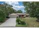 Inviting home with lush landscaping, spacious driveway, well-maintained lawn, and a pop of color from the red entry door at 5443 Ott Ct, Spring Hill, FL 34608