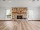 Spacious living room with stone fireplace, wood flooring, and natural light from the windows at 5443 Ott Ct, Spring Hill, FL 34608