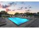 A refreshing community pool with modern lounge furniture and decorative umbrellas under a colorful evening sky at 6213 64Th N Way, Pinellas Park, FL 33781
