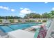 The clear blue community pool is surrounded by lounge chairs, patio furniture, and lush green landscaping at 6213 64Th N Way, Pinellas Park, FL 33781