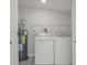 Functional laundry room with modern washer, dryer, water heater, and built in wire shelving at 6291 63Rd N St, Pinellas Park, FL 33781