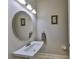 Elegant powder room features a sleek oval mirror and modern wall-mounted sink at 6640 Park Strand Dr, Apollo Beach, FL 33572