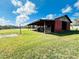 Exterior view of the barn with open doors and a covered area, set against a beautiful landscape at 7705 W Four Pines Rd, Plant City, FL 33565