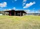 Red barn with open sides, picnic tables and a view of an adjacent farmhouse at 7705 W Four Pines Rd, Plant City, FL 33565