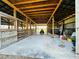 Inside the barn: Concrete floor, exposed wood beam ceiling and open stalls at 7705 W Four Pines Rd, Plant City, FL 33565