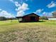 Rustic red barn featuring open doors, a covered area, and a serene pond view at 7705 W Four Pines Rd, Plant City, FL 33565