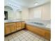 Bathroom with double vanity, built-in tub, tiled floor, and large mirrors at 7705 W Four Pines Rd, Plant City, FL 33565