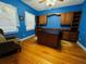 Bedroom with blue walls, wood floors, custom cabinets, and built-in desk with storage at 7705 W Four Pines Rd, Plant City, FL 33565