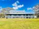 A spacious farmhouse with a wide, covered porch overlooking a yard at 7705 W Four Pines Rd, Plant City, FL 33565