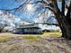 Two-story home with wraparound porch, blue siding, and a red barn on a tree-filled lot at 7705 W Four Pines Rd, Plant City, FL 33565