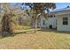 The grassy backyard offers views of the mature trees and a screened patio at 9911 Mendel Dr, New Port Richey, FL 34654