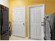 Well-organized laundry room with a refrigerator, washer, dryer, and two entry doors at 9911 Mendel Dr, New Port Richey, FL 34654