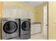 Practical laundry room featuring modern machines, a sink, and storage above the appliances at 9911 Mendel Dr, New Port Richey, FL 34654