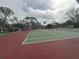 Outdoor tennis courts with green and red surface surrounded by trees at 121 Loblolly Ct # H, Oldsmar, FL 34677