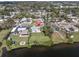 Aerial view of a waterfront home with well-maintained lawn, fire pit, and tiki hut at 1230 75Th N Ave, St Petersburg, FL 33702